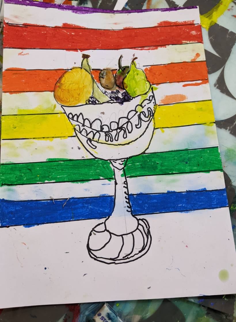 A goblet of fruit on a rainbow-striped background