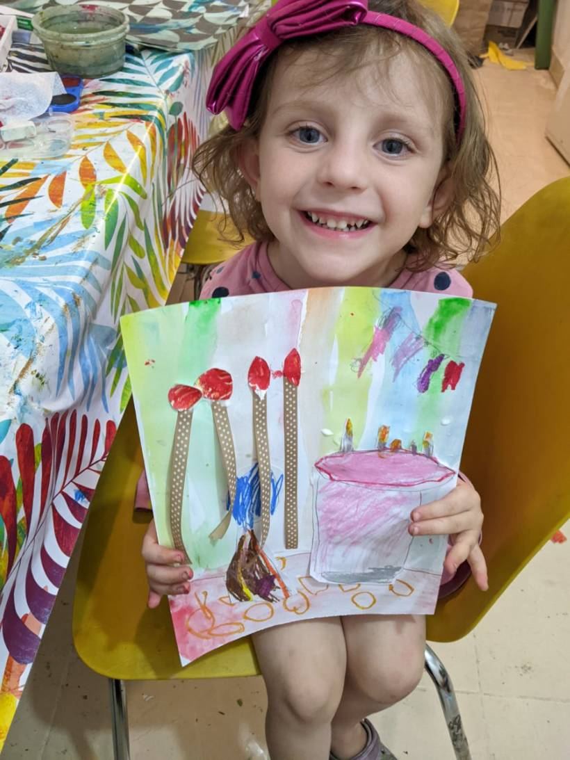 A young girl beaming with her painting