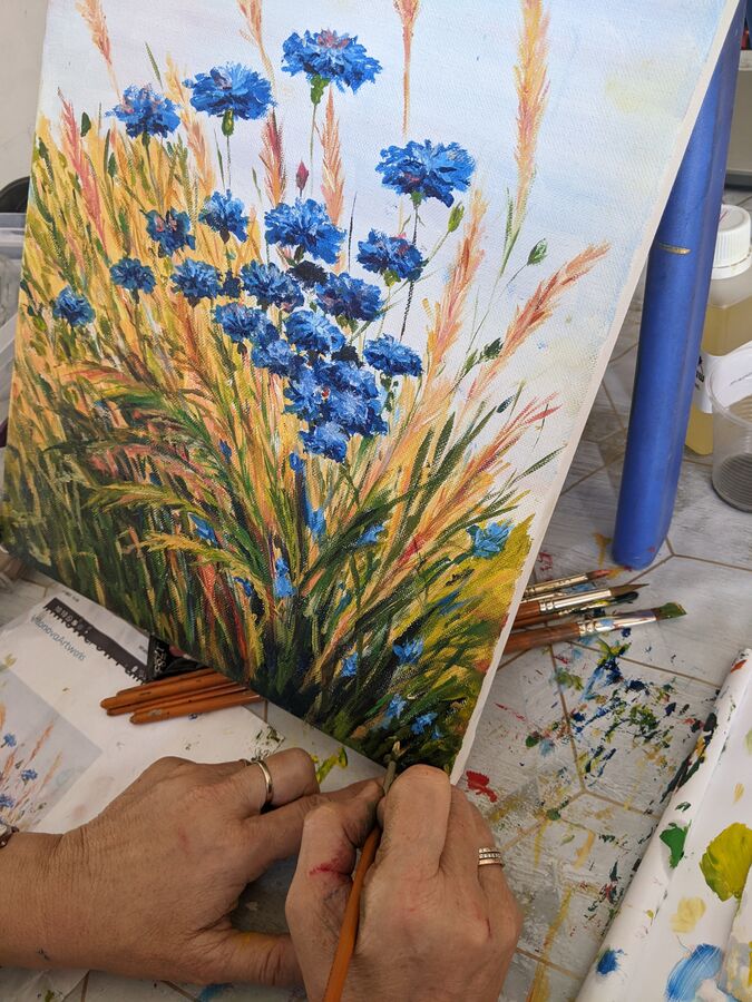 Adult student painting cornflowers in acrylics